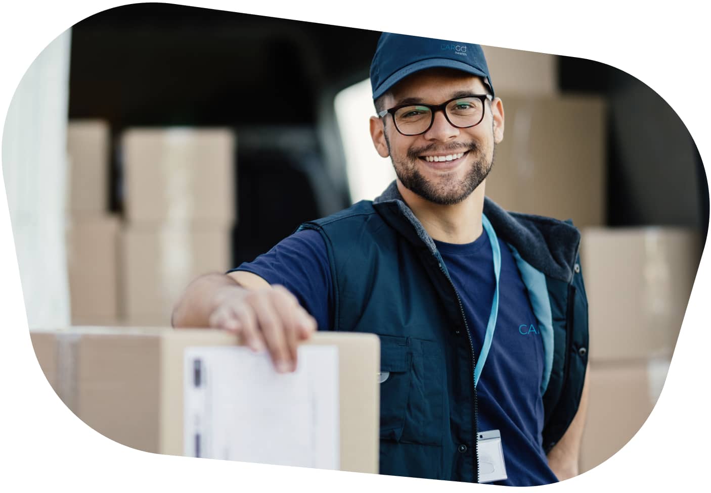 A smiling carGO Health medical courier, leaning on a stack of boxes in a delivery vehicle.