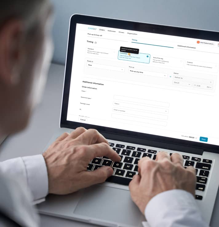 A doctor using a laptop to enter delivery details on the carGO Health web application.